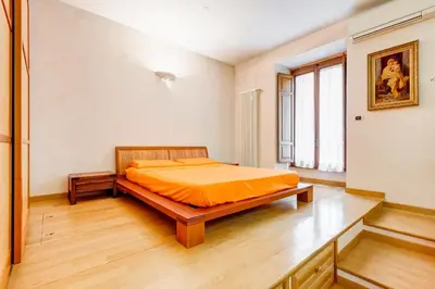 a bedroom with a bed with an orange bedspread at Vatican - Zen Style loft with Jacuzzi in Rome