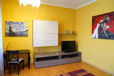 a living room with a tv and a desk and a painting at the sun in rome in Rome