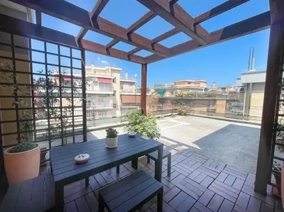 a patio with a wooden table and bench on a balcony at the sun in rome in Rome