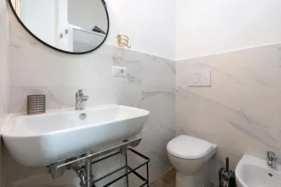 a white bathroom with a sink and a mirror at Molly Home in Rome
