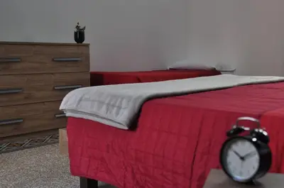 a bedroom with two beds with red sheets and an alarm clock at Big House Colosseo in Rome