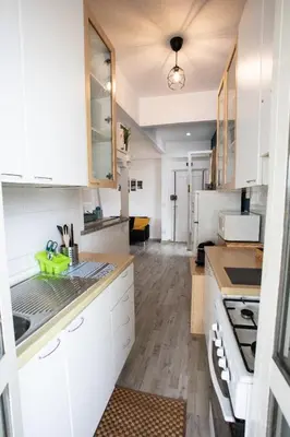 a kitchen with white cabinets and wooden floors at Belvedere pigneto in Rome