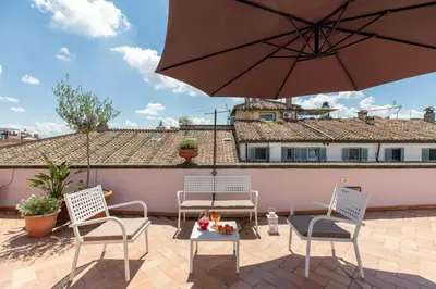 a patio with two chairs and a table and an umbrella at iFlat Penthouse in Campo de' Fiori in Rome