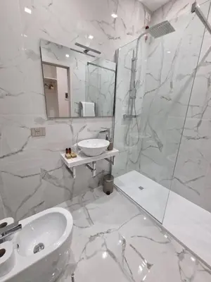 a white bathroom with a sink and a shower at Cuma Suites in Rome