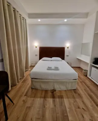 a bedroom with a large bed and wooden floors at Cuma Suites in Rome