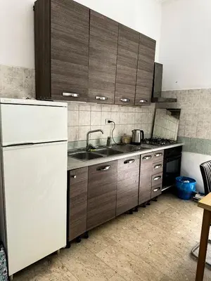 a kitchen with a white refrigerator and wooden cabinets at Sina Rent Room in Rome