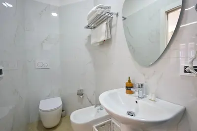 a white bathroom with a sink and a toilet at Rohome Stay in Rome
