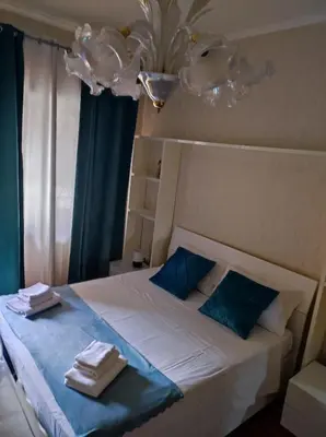 a bedroom with a bed with blue sheets and a chandelier at Vacanze romane in Rome