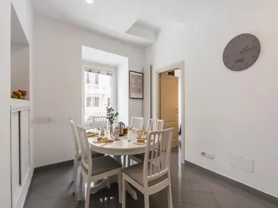 a dining room with a table and chairs and a clock at The Best Rent - Two-bedroom apartment in Colosseum area in Rome