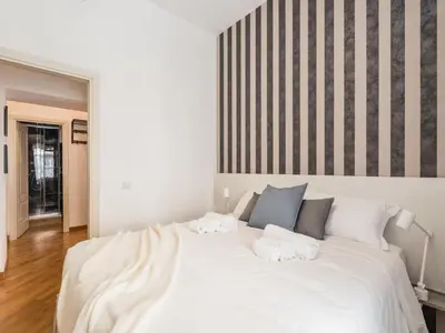 a large white bed with two towels on it at The Best Rent - Spacious three-bedroom apartment near the Colosseum in Rome