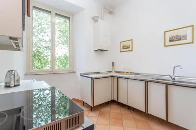 a kitchen with white walls and a large window at Daplace - Beatrice Apartment in Rome