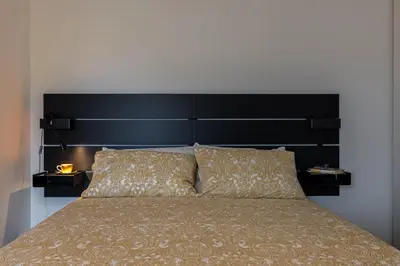 a bed with a large black headboard and two pillows at Suite close to Vatican City - Ingresso Spa in Rome