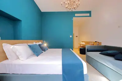 a blue bedroom with a large bed and a couch at Youroom Quattro Fontane - Rooms in Rome