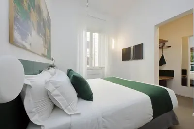 a bedroom with a white bed with green and white pillows at YCH-Montebello - Rooms in Rome
