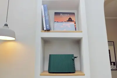 a book shelf with books and a green suitcase on it at YCH-Montebello - Rooms in Rome