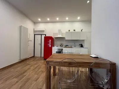 a kitchen with a wooden table and a red refrigerator at La Dolce Vita - Luxury Colosseum Boutique Apartment in Rome