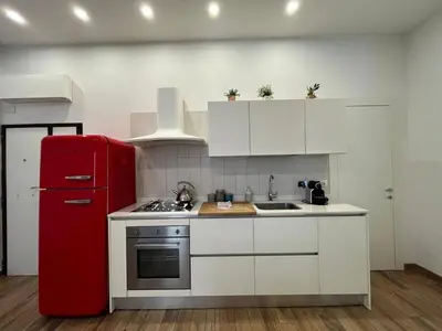 a kitchen with a red refrigerator and white cabinets at La Dolce Vita - Luxury Colosseum Boutique Apartment in Rome
