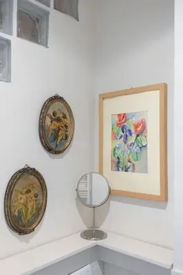 a white wall with two pictures and a mirror on a shelf at La Dolce Vita - Old Testaccio Authentic District in Rome