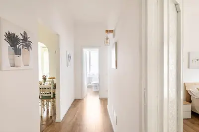 a living room with white walls and a wooden floor at tibershome home la casa sul tevere in Rome