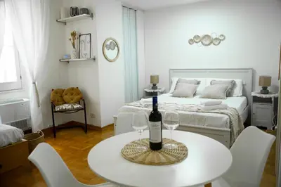 a white room with a table with a bottle of wine at Shabby Roman Studio- ai fori Imperiali in Rome