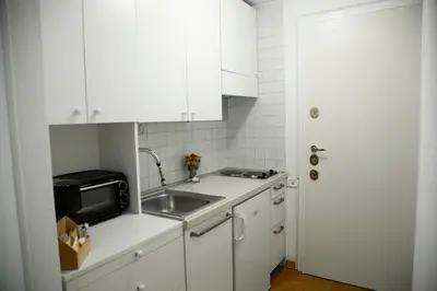 a white kitchen with a sink and a microwave at Shabby Roman Studio- ai fori Imperiali in Rome