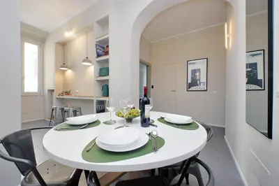 a white dining room with a white table and chairs at Youcomehere - Montebello in Rome