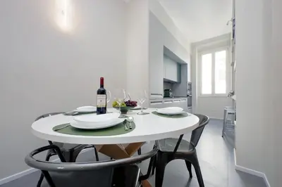 a white dining room table with a bottle of wine at Youcomehere - Montebello in Rome
