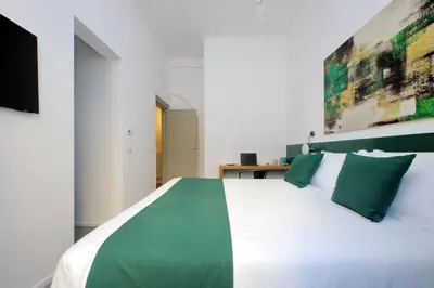 a bedroom with a large white bed with green pillows at Youcomehere - Montebello in Rome