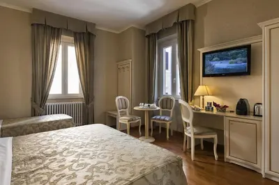 a hotel room with a bed and a desk and chairs at Relais Bocca di Leone in Rome