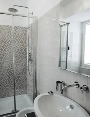 a white bathroom with a shower and a sink at Relais Bocca di Leone in Rome