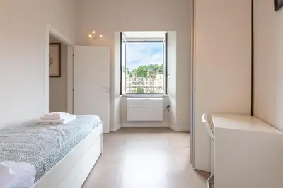 a white bedroom with a bed and a window at Trastevere at heart in Rome