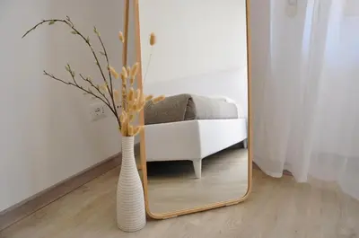 a mirror with a white vase in front of a chair at Cozy home close to the city center in Rome