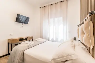 a white bedroom with a bed and a tv at Casa Roma B&B in Rome