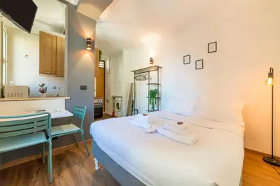 a bedroom with a large white bed and a kitchen at Studio in Trastevere Village in Rome