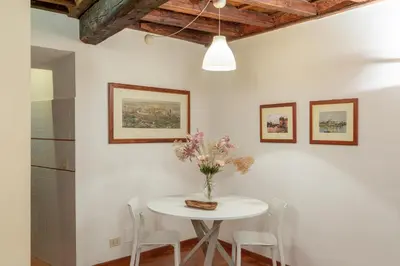 a white table with chairs and a vase of flowers on it at iFlat Comfy Apartament in Campo de' Fiori in Rome