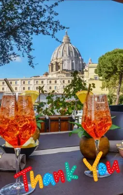 two wine glasses sitting on a table in front of a building at San Pietro Shabby Chic Apartment in Rome