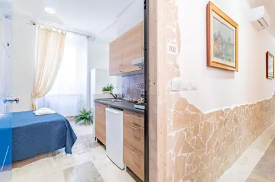 a white bedroom with a blue bed with two lamps at BARONE HOUSE in Rome
