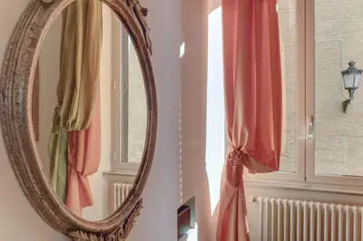 a mirror hanging on a wall next to a window at Colosseo Residenza Sette Sale in Rome