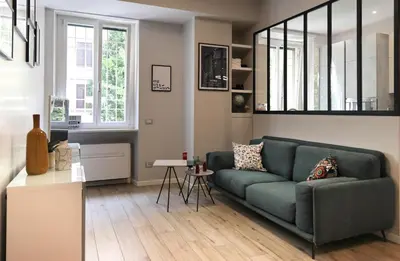 a living room with a green couch and a kitchen at Suite RHome In Vatican in Rome