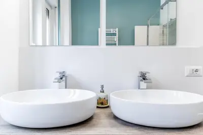 two white sinks in a bathroom with mirrors at BBHOME History and design apartment in Testaccio district in Rome
