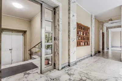 an empty hallway with marble floors and glass doors at BBHOME History and design apartment in Testaccio district in Rome