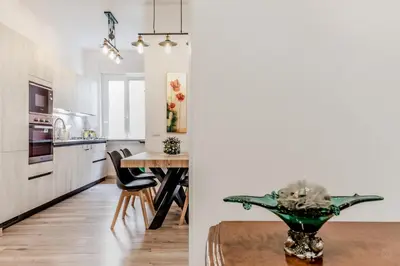 a kitchen and dining room with a table and a kitchen with white cabinets at BBHOME History and design apartment in Testaccio district in Rome