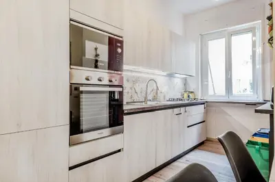 a white kitchen with a sink and a stove at BBHOME History and design apartment in Testaccio district in Rome
