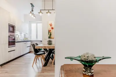 a kitchen and dining room with a table and a kitchen with white cabinets at BBHOME History and design apartment in Testaccio district in Rome