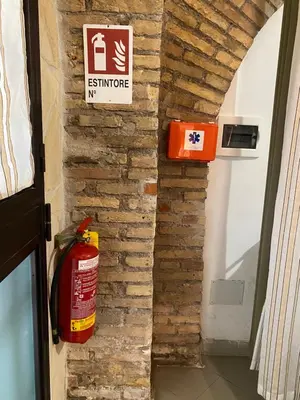 a fire extinguisher sign and a fire hydrant on a brick wall at apartment vittorio Emanuele in Rome