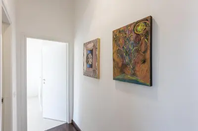 three paintings are hanging on a white wall at Corso View by Rental in Rome in Rome