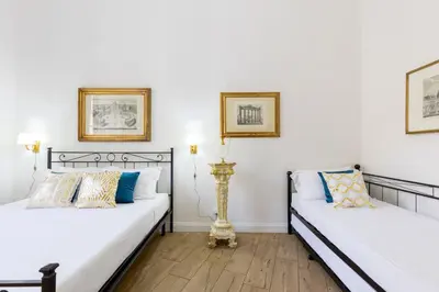 two beds in a room with white walls at Ottaviano Suites in Rome
