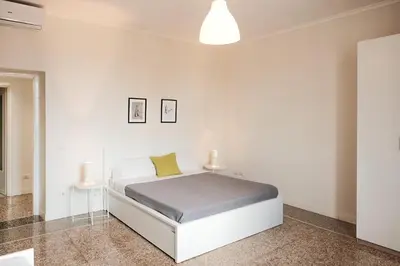 a white bedroom with a white bed and two tables at Family apartment near Vatican Museum in Rome