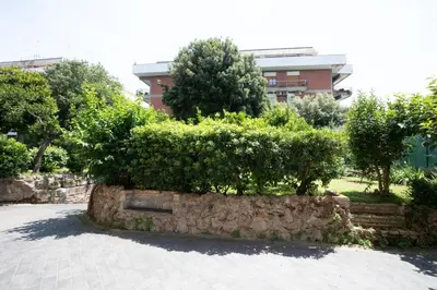a stone wall with bushes and trees in front of a building at Domus Cordara - Splendido appartamento nel verde in Rome