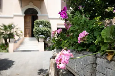 a retaining wall with pink flowers in front of a house at Domus Cordara - Splendido appartamento nel verde in Rome